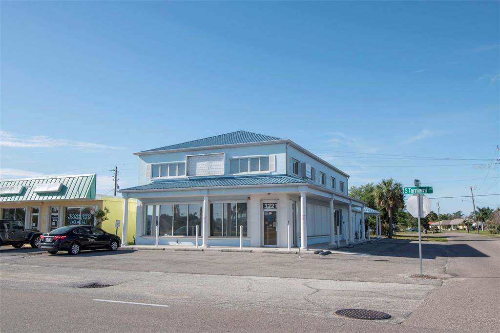 A two-story light blue commercial building with a metal roof sits on a corner lot — 3221 TAMIAMI TRL UNIT 16, PORT CHARLOTTE, FL