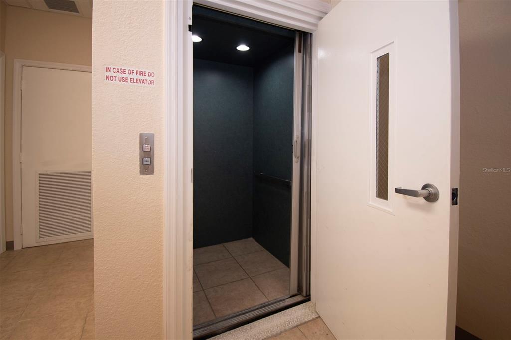 An open elevator with tiled flooring is situated between two white doors in a hallway — 3221 TAMIAMI TRL UNIT 16, PORT CHARLOTTE, FL