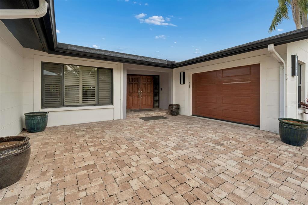 A paved courtyard leads to a front entrance with double wooden doors and a garage — 4213 SALTWATER BOULEVARD, TAMPA, FL