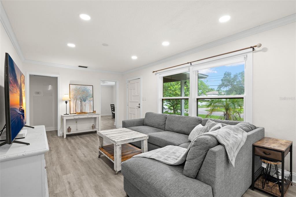A living room features a gray sectional sofa, a white coffee table, and light wood flooring — 3822 W EUCLID AVENUE, TAMPA, FL