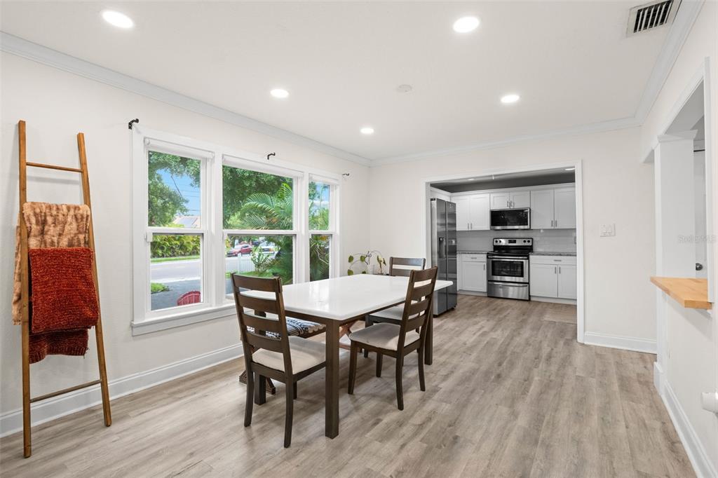 A dining area with wood-look flooring, a white table, and a view into the kitchen — 3822 W EUCLID AVENUE, TAMPA, FL