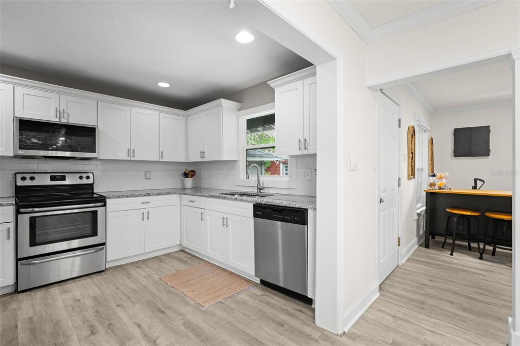 A kitchen with white cabinets, stainless steel appliances, and light wood-look flooring — 3822 W EUCLID AVENUE, TAMPA, FL