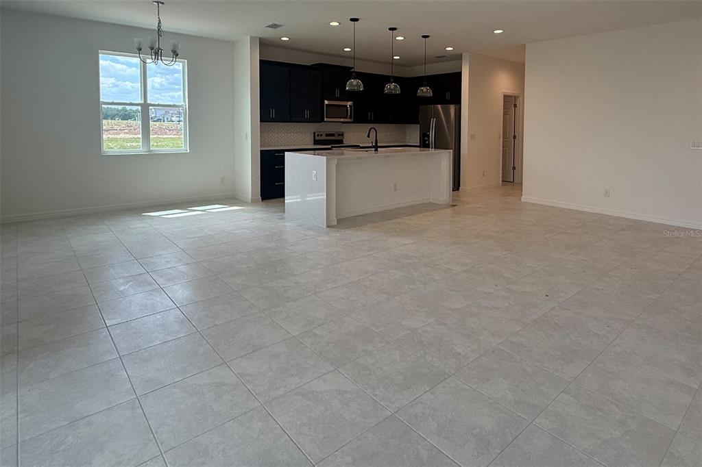An open-concept kitchen features dark cabinets, a white island, and light tile flooring — 7171 ROLLING LEAF ROAD, GROVELAND, FL