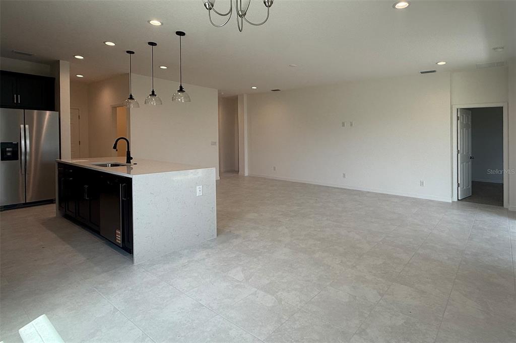 A kitchen with a large island and stainless steel appliances opens into a spacious living area — 7171 ROLLING LEAF ROAD, GROVELAND, FL