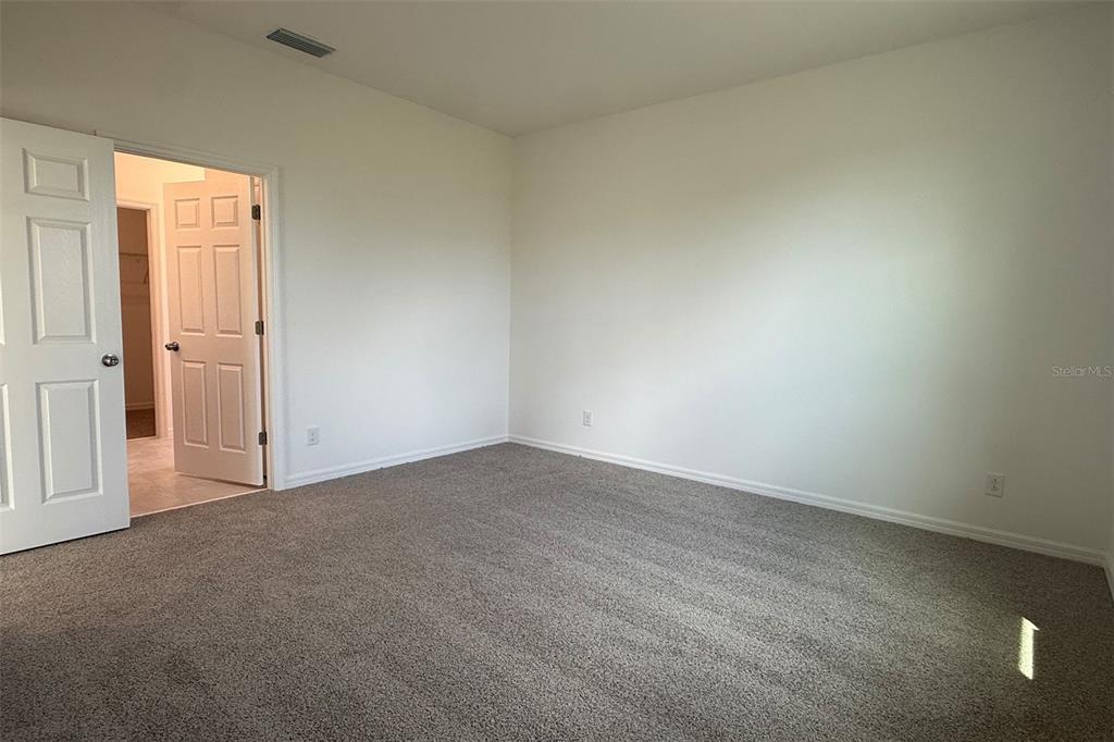 An empty bedroom features gray carpet, white walls, and an open door to a closet — 7171 ROLLING LEAF ROAD, GROVELAND, FL