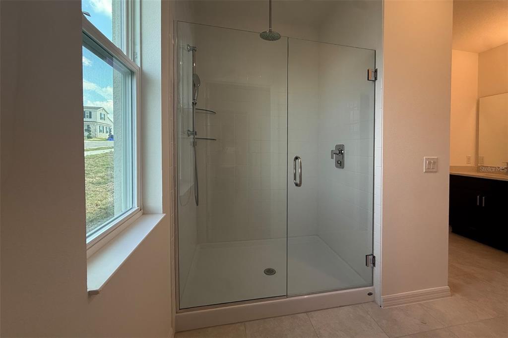 A walk-in shower with a glass door and a window sits in a modern bathroom — 7171 ROLLING LEAF ROAD, GROVELAND, FL