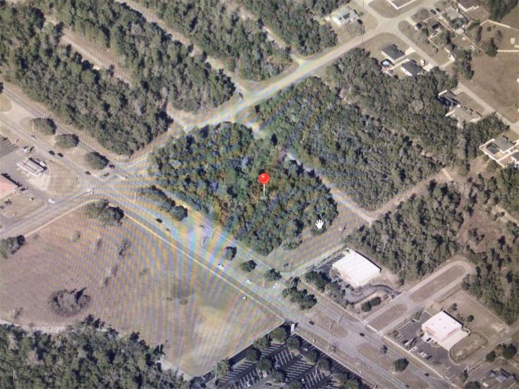 An aerial view shows a wooded plot of land marked with a red pin — 0 MARION OAKS BOULEVARD, OCALA, FL