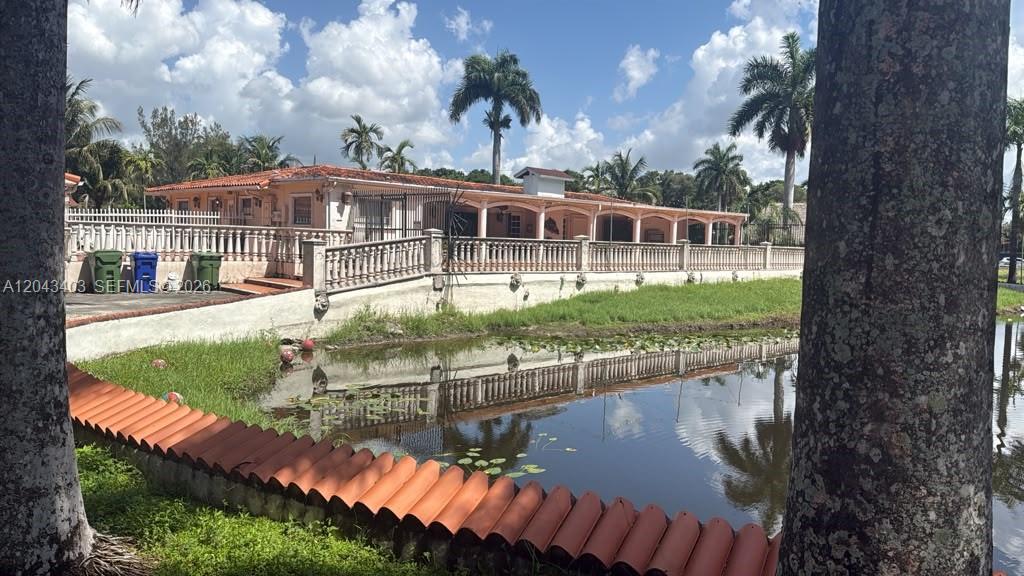 A single-story house with a terracotta roof sits behind a pond and stone balustrade — 4000 SW 126th Ave, Miramar FL 33027, MIRAMAR, FL