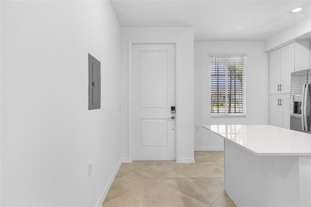 A bright kitchen features white cabinets, a quartz island, tile flooring, and a white door — 14191 HERITAGE LANDING BOULEVARD UNIT 1214, PUNTA GORDA, FL