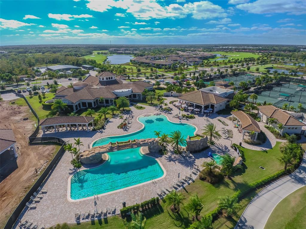 An aerial view shows a large community swimming pool with a rock waterfall feature — 18114 GAWTHROP DRIVE UNIT 106, BRADENTON, FL