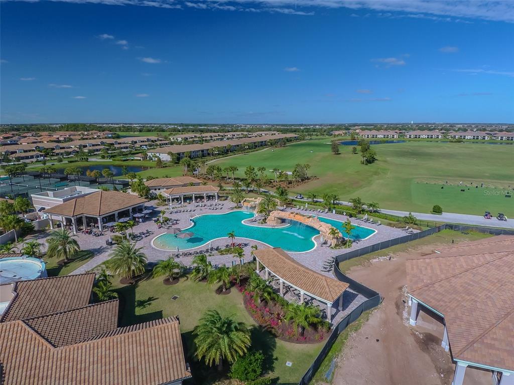 An aerial view shows a community swimming pool with a rock waterfall and surrounding buildings — 18114 GAWTHROP DRIVE UNIT 106, BRADENTON, FL