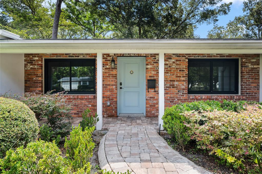 A brick house exterior features a light blue front door and a stone walkway — 648 FITZWALTER DRIVE, WINTER PARK, FL