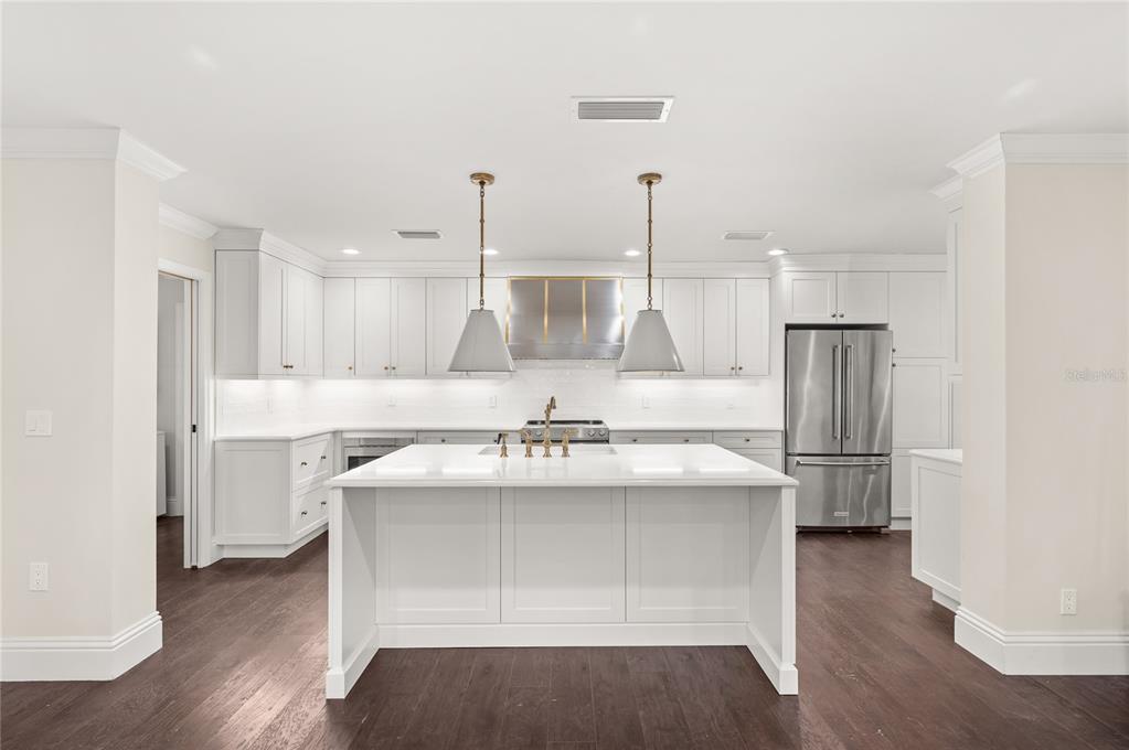 A modern white kitchen features a central island, stainless steel appliances, and dark wood flooring — 648 FITZWALTER DRIVE, WINTER PARK, FL