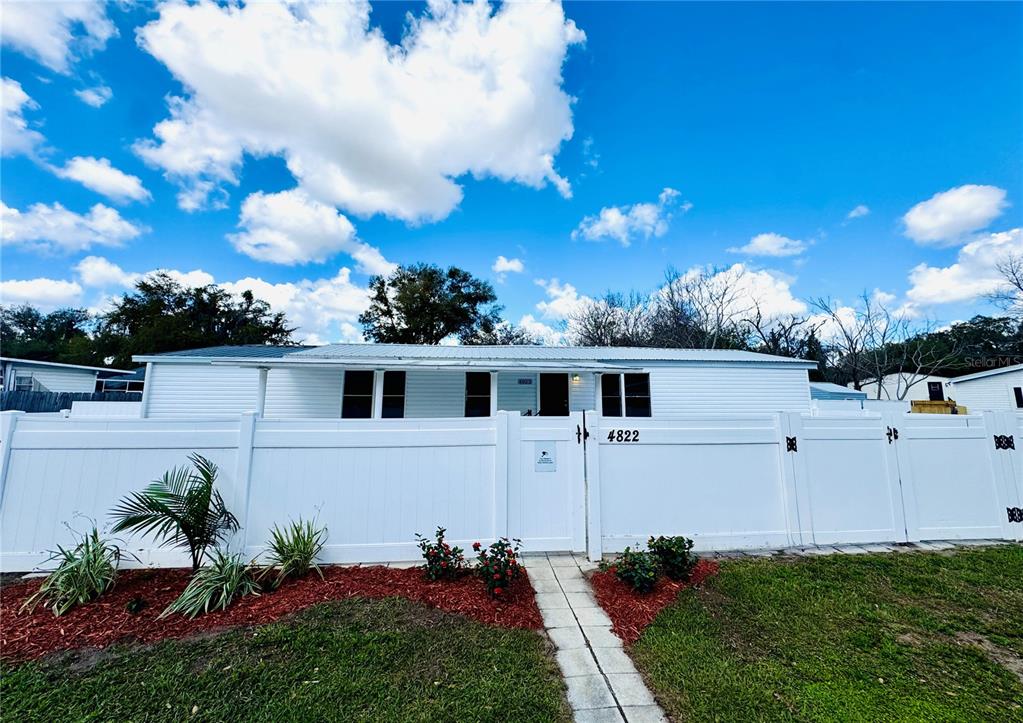 A white single-story house is enclosed by a white vinyl privacy fence — 4822 ROLLING MEADOW DRIVE, LAKELAND, FL