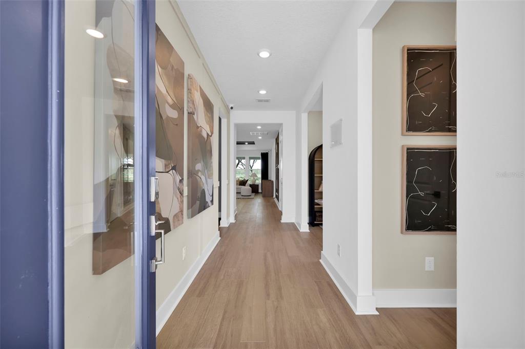 A bright entryway features light wood flooring, white walls, and abstract wall art — 81 LAKE MANATEE DRIVE, PALM COAST, FL
