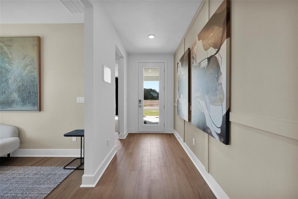 A hallway with wood-look flooring, board and batten walls, and a glass-paneled front door — 81 LAKE MANATEE DRIVE, PALM COAST, FL