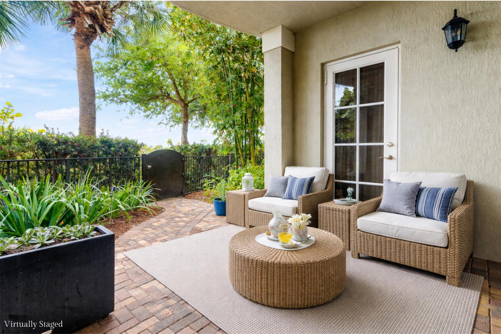 A patio with wicker furniture, a rug, and a brick floor overlooks a garden area — 144 Tierra Lane # 11, Jupiter FL 33477, JUPITER, FL