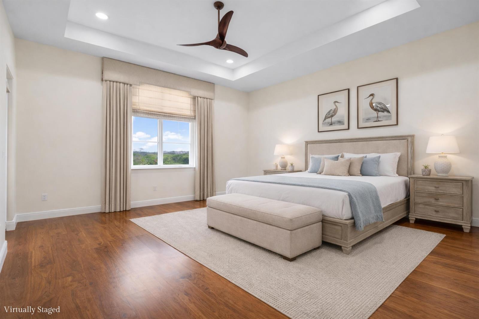 A bedroom with a tray ceiling, wood floors, and a king-sized bed with neutral bedding — 144 Tierra Lane # 11, Jupiter FL 33477, JUPITER, FL