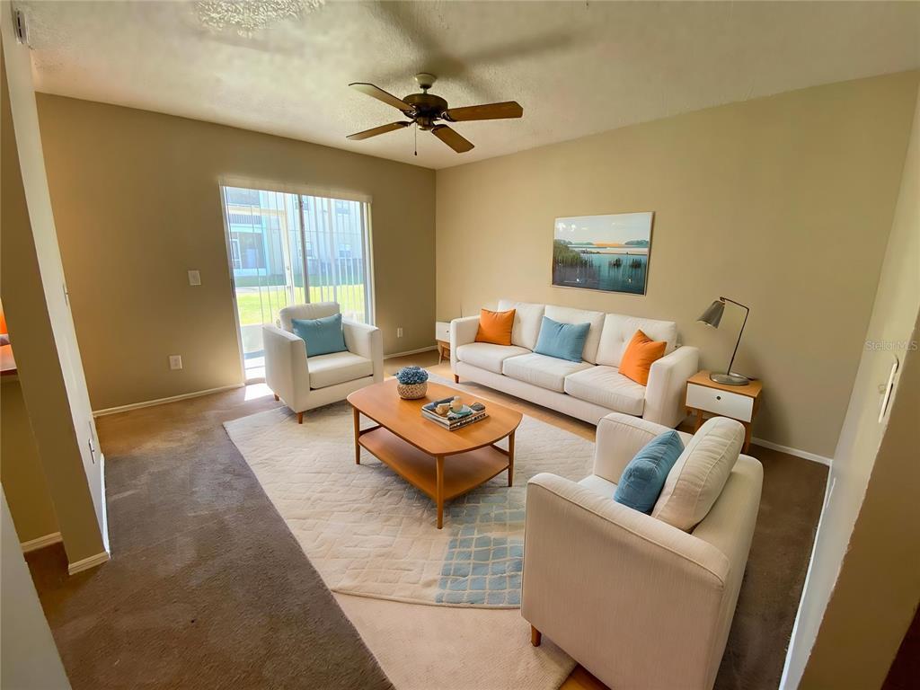 A living room features a white sofa, two armchairs, a coffee table, and sliding doors — 4148 PERSHING POINTE PLACE UNIT 1, ORLANDO, FL