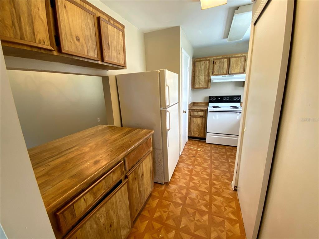 A kitchen features wood cabinets, a white refrigerator, and a white stove on patterned flooring — 4148 PERSHING POINTE PLACE UNIT 1, ORLANDO, FL