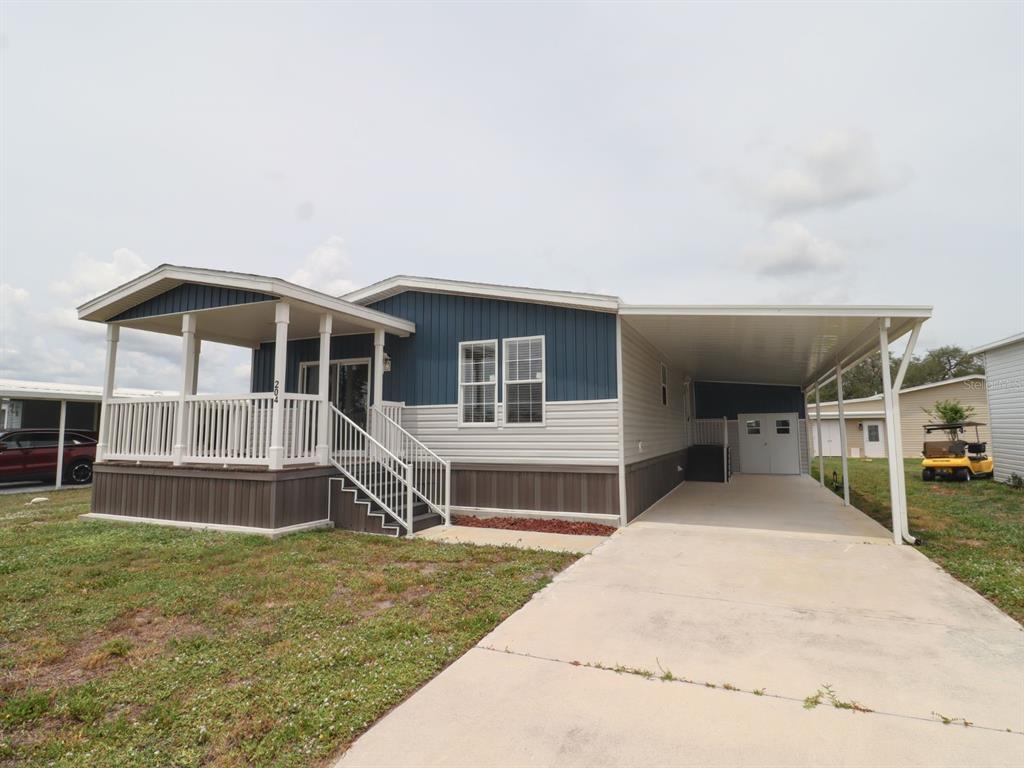 A manufactured home with a front porch, carport, and blue and beige siding — 204 EL PRADO, NORTH PORT, FL