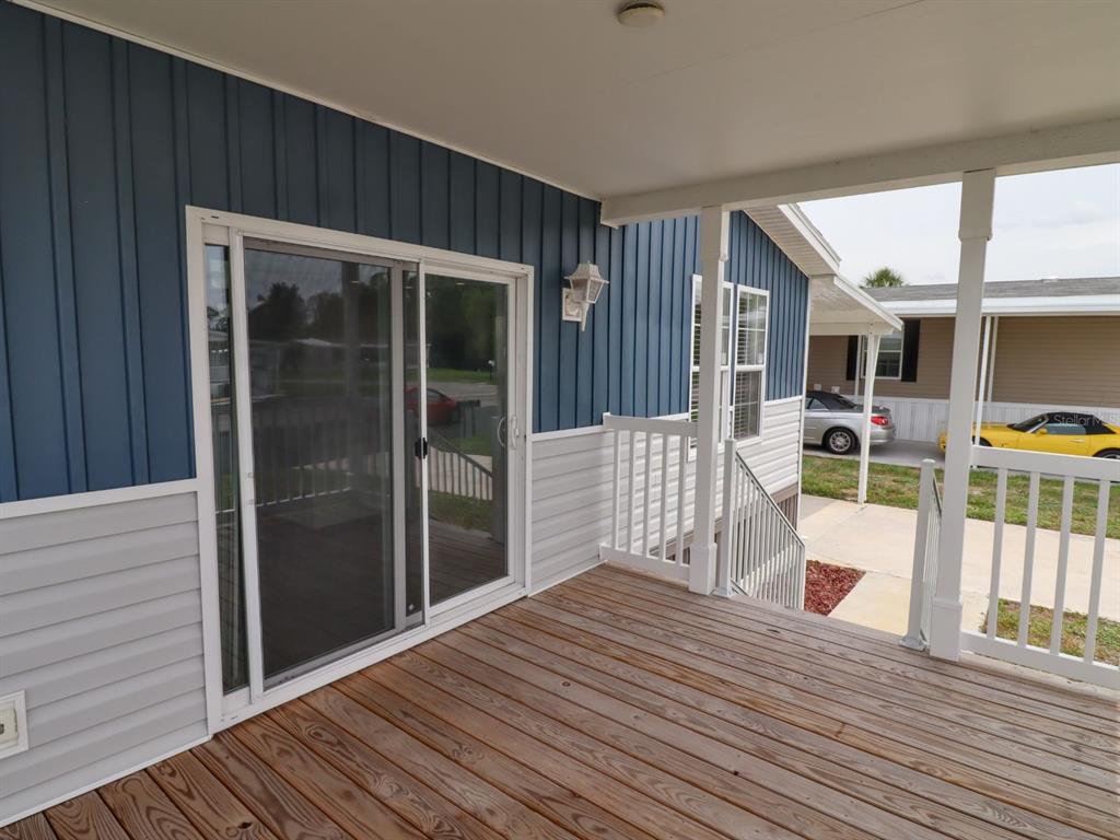 A wooden deck with a sliding glass door and blue and white vertical siding — 204 EL PRADO, NORTH PORT, FL