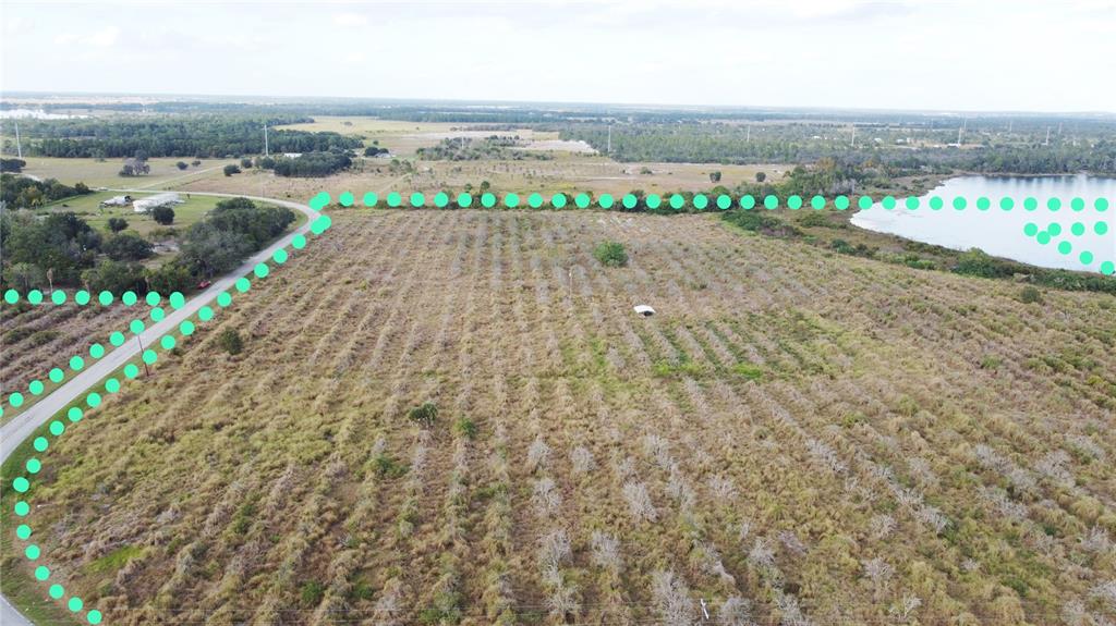 An aerial view shows a large, undeveloped plot of land bordered by a road and lake — 7630 LAKE BUFFUM ROAD N, FORT MEADE, FL