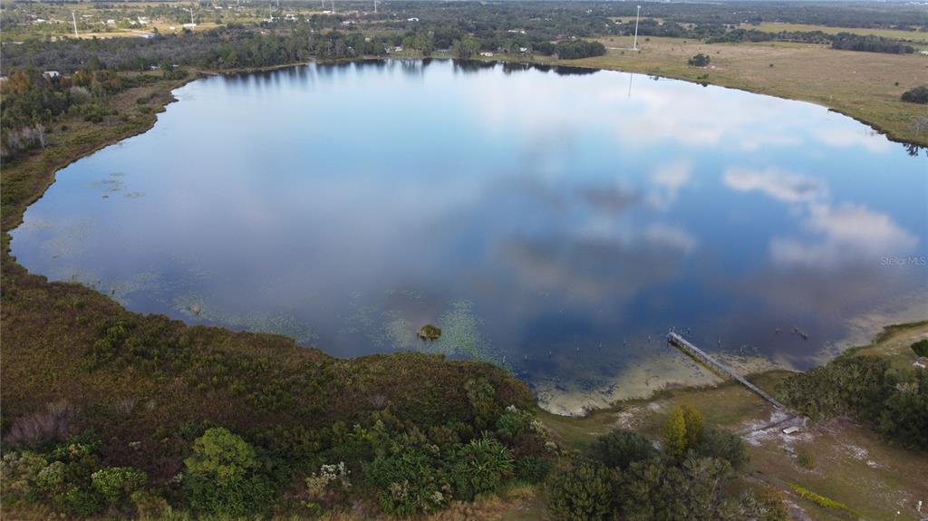 An aerial view shows a large lake with a wooden dock extending into the water — 7630 LAKE BUFFUM ROAD N, FORT MEADE, FL