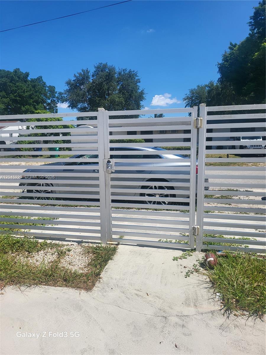 A white horizontal-slat metal gate stands in front of a parked silver car — 2467 NW 95th Ter, Miami FL 33147, MIAMI, FL