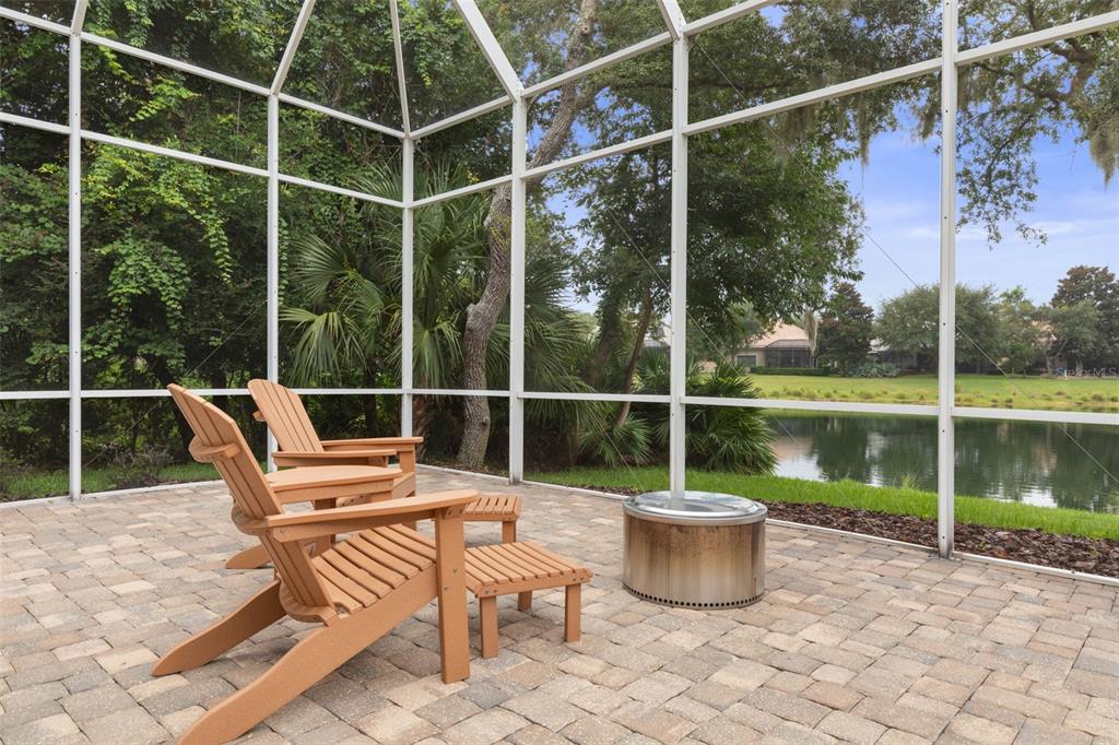 A screened-in patio features two wooden chairs, a small table, and a metal fire pit — 10 N VILLAGE PARKWAY, PALM COAST, FL