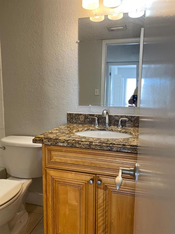 A bathroom features a wood vanity with a granite countertop, a sink, and a mirror — 4749 S TEXAS AVENUE UNIT 4749C, ORLANDO, FL