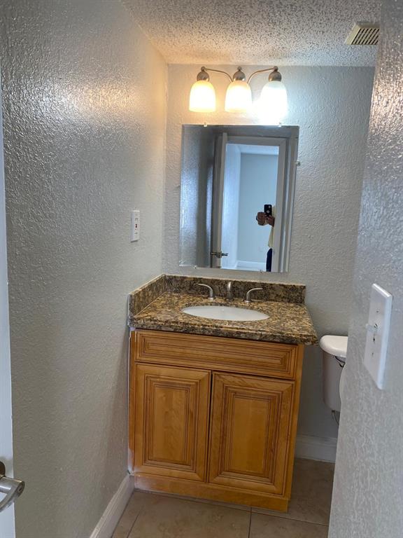 A bathroom features a wooden vanity with a granite countertop, a mirror, and overhead lighting — 4749 S TEXAS AVENUE UNIT 4749C, ORLANDO, FL