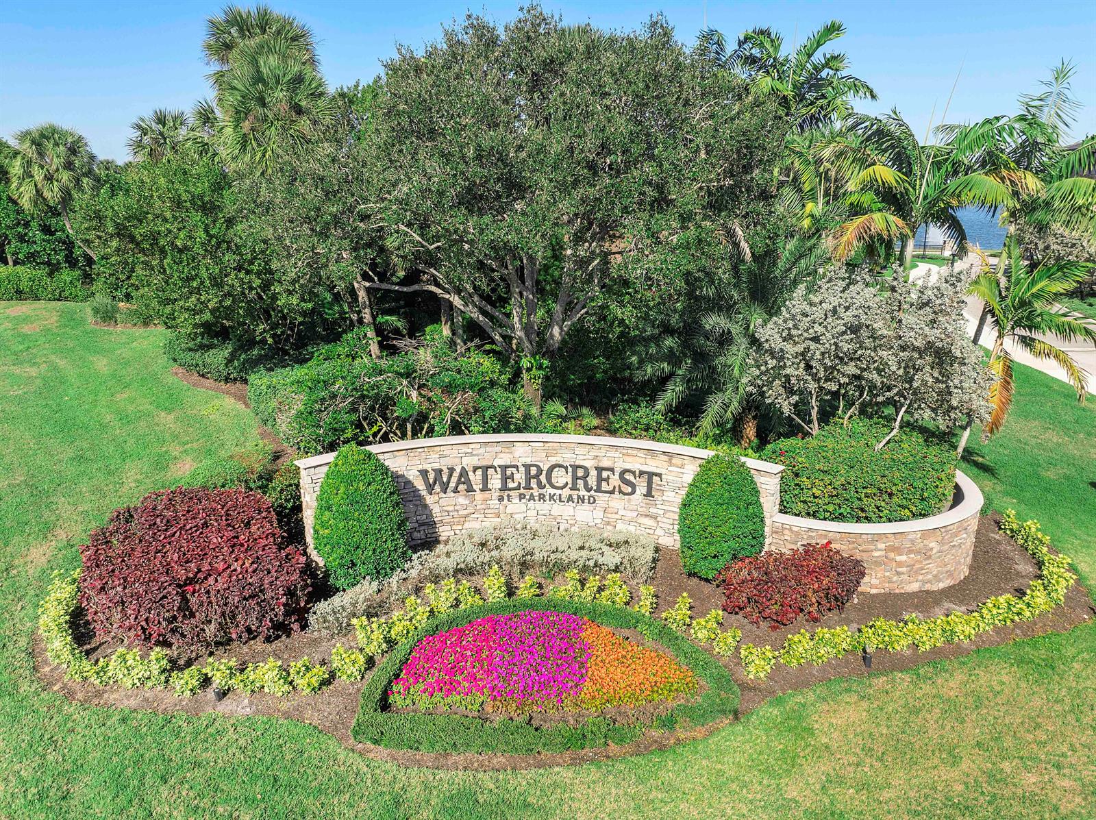 An aerial view shows the stone entrance sign for Watercrest at Parkland surrounded by landscaping — 11425 Watercrest Circle E, Parkland FL 33076, PARKLAND, FL