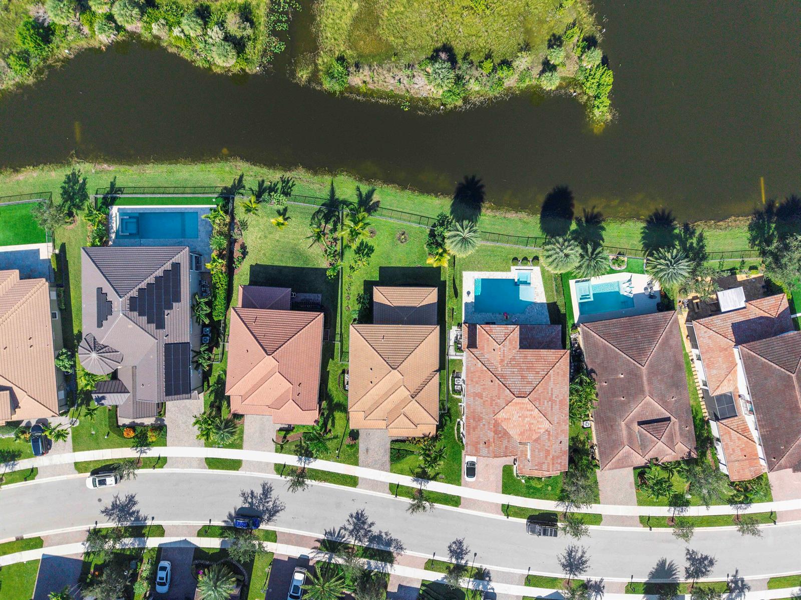 An aerial view shows several suburban houses with swimming pools situated along a waterfront — 11425 Watercrest Circle E, Parkland FL 33076, PARKLAND, FL