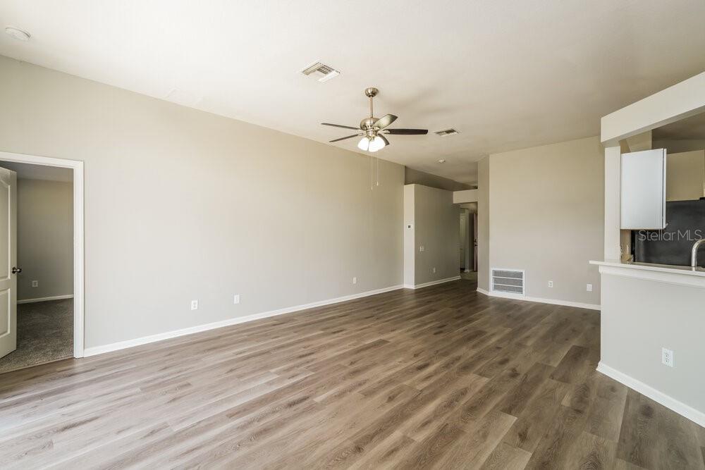 An empty living room features light gray walls, wood-look flooring, and a ceiling fan — 12534 HERONS PATH PLACE, RIVERVIEW, FL