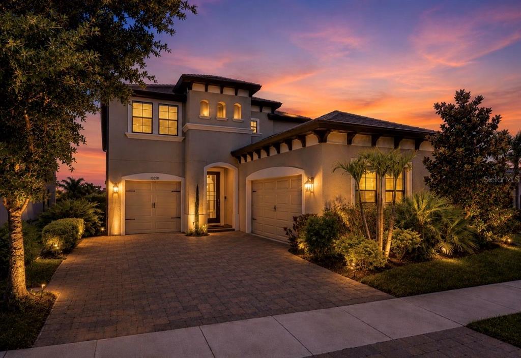 A two-story house with a paved driveway and two garages at sunset — 13107 MONACH ISLES DRIVE, RIVERVIEW, FL
