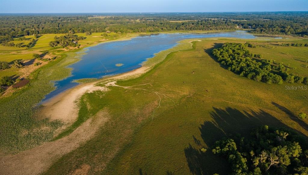 An aerial view shows a large lake surrounded by expansive green pastures and wooded areas — MONDON HILL ROAD, BROOKSVILLE, FL