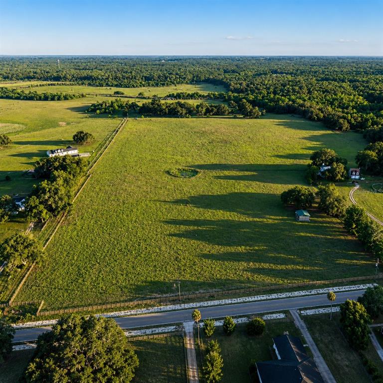 An aerial view shows a large, grassy, fenced-in pasture with a small pond and trees — MONDON HILL ROAD, BROOKSVILLE, FL