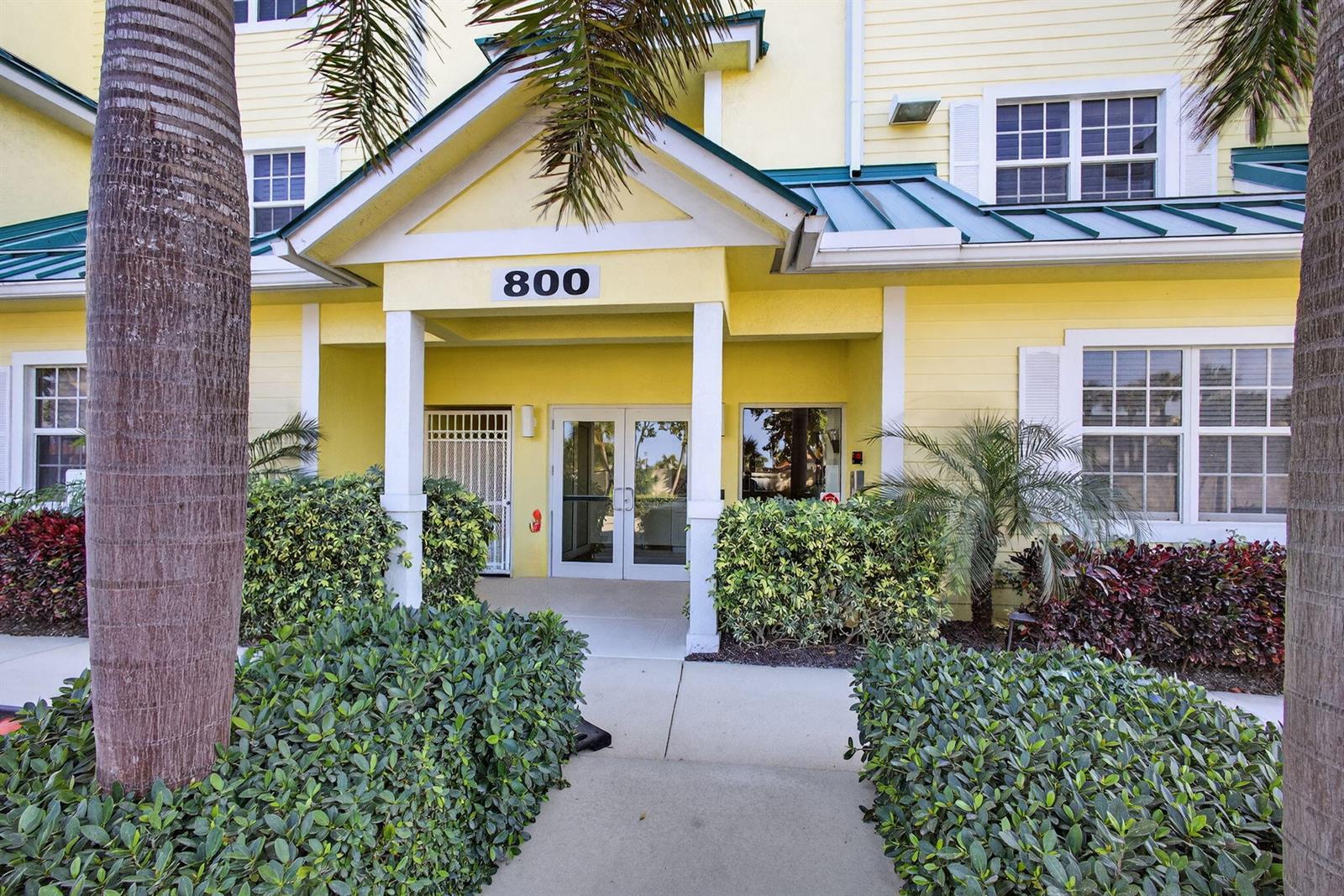 The exterior of a yellow building with a covered entrance marked with the number 800 — 800 Juno Ocean Walk # 304, Juno Beach FL 33408, JUNO BEACH, FL