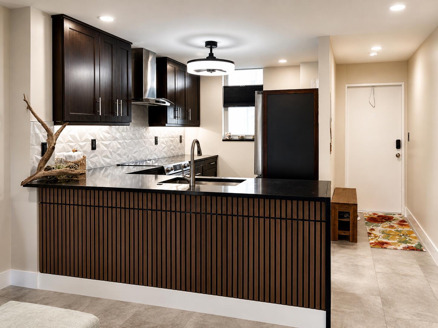 A modern kitchen features dark wood cabinets, a slatted wood island, and black countertops — 9940 S Ocean Drive # 802, Jensen Beach FL 34957, JENSEN BEACH, FL