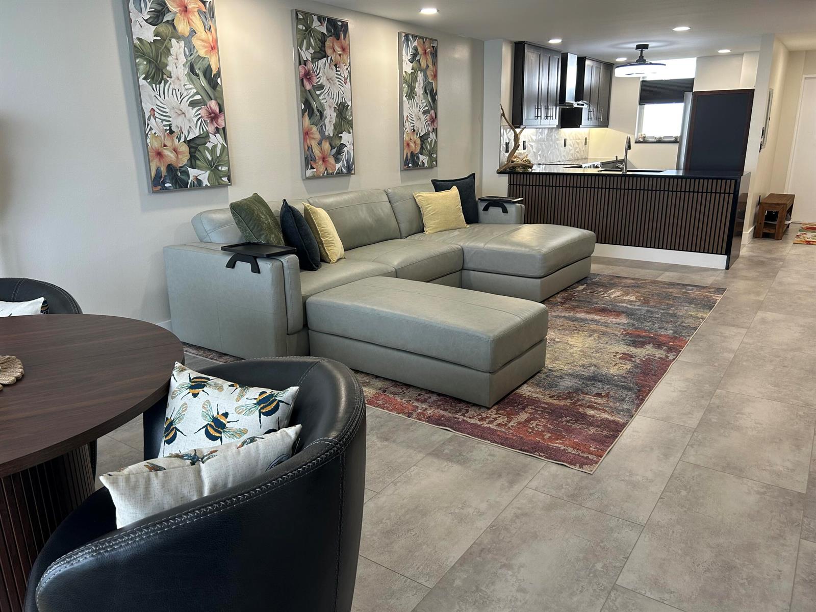 A living room with a gray sectional sofa, patterned rug, and an open kitchen area — 9940 S Ocean Drive # 802, Jensen Beach FL 34957, JENSEN BEACH, FL
