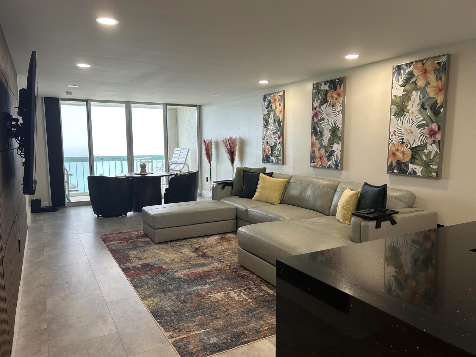 A living room features a grey sectional sofa, a patterned area rug, and balcony views — 9940 S Ocean Drive # 802, Jensen Beach FL 34957, JENSEN BEACH, FL