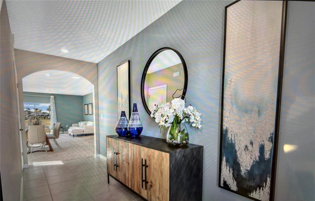 A foyer features a wood-and-metal console table, a round mirror, and artwork against blue walls — 3464 SANDALWOOD ISLE WAY, OCOEE, FL