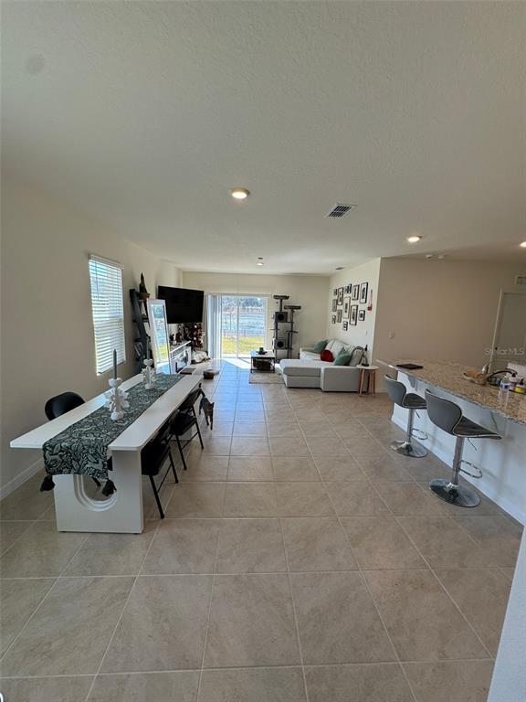 An open-concept living and dining area features tile flooring, a kitchen island, and sliding doors — 3464 SANDALWOOD ISLE WAY, OCOEE, FL