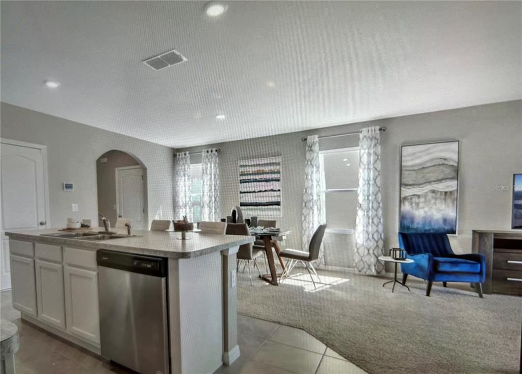 A kitchen island with a stainless steel dishwasher overlooks a dining area and living space — 3464 SANDALWOOD ISLE WAY, OCOEE, FL