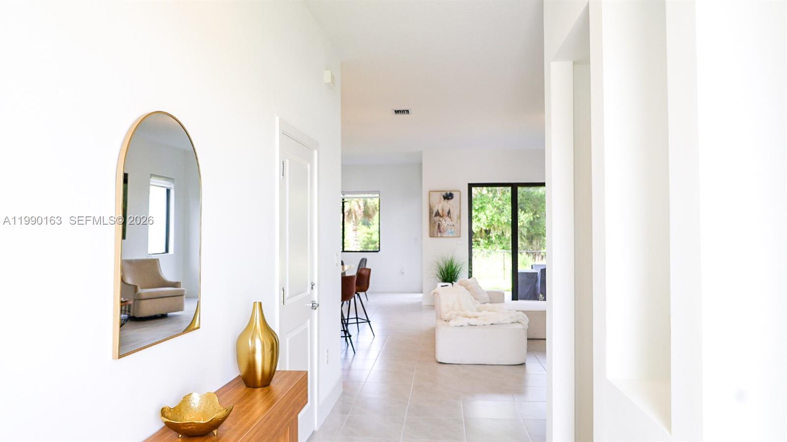 A bright hallway leads into an open-concept living area with light tile flooring — 5868 Agostino Way, Ave Maria FL 34142, AVE MARIA, FL