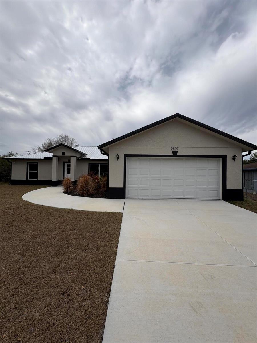 A single-story house with a white stucco exterior, dark trim, and a two-car garage — 2897 NW 37th Avenue, Okeechobee FL 34972, OKEECHOBEE, FL