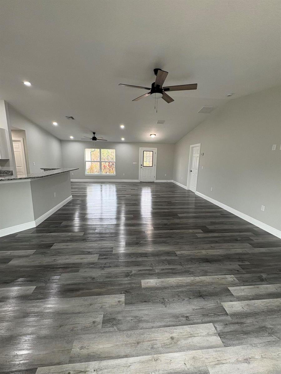 An open-concept living area features gray wood-look flooring, recessed lighting, and two ceiling fans — 2897 NW 37th Avenue, Okeechobee FL 34972, OKEECHOBEE, FL