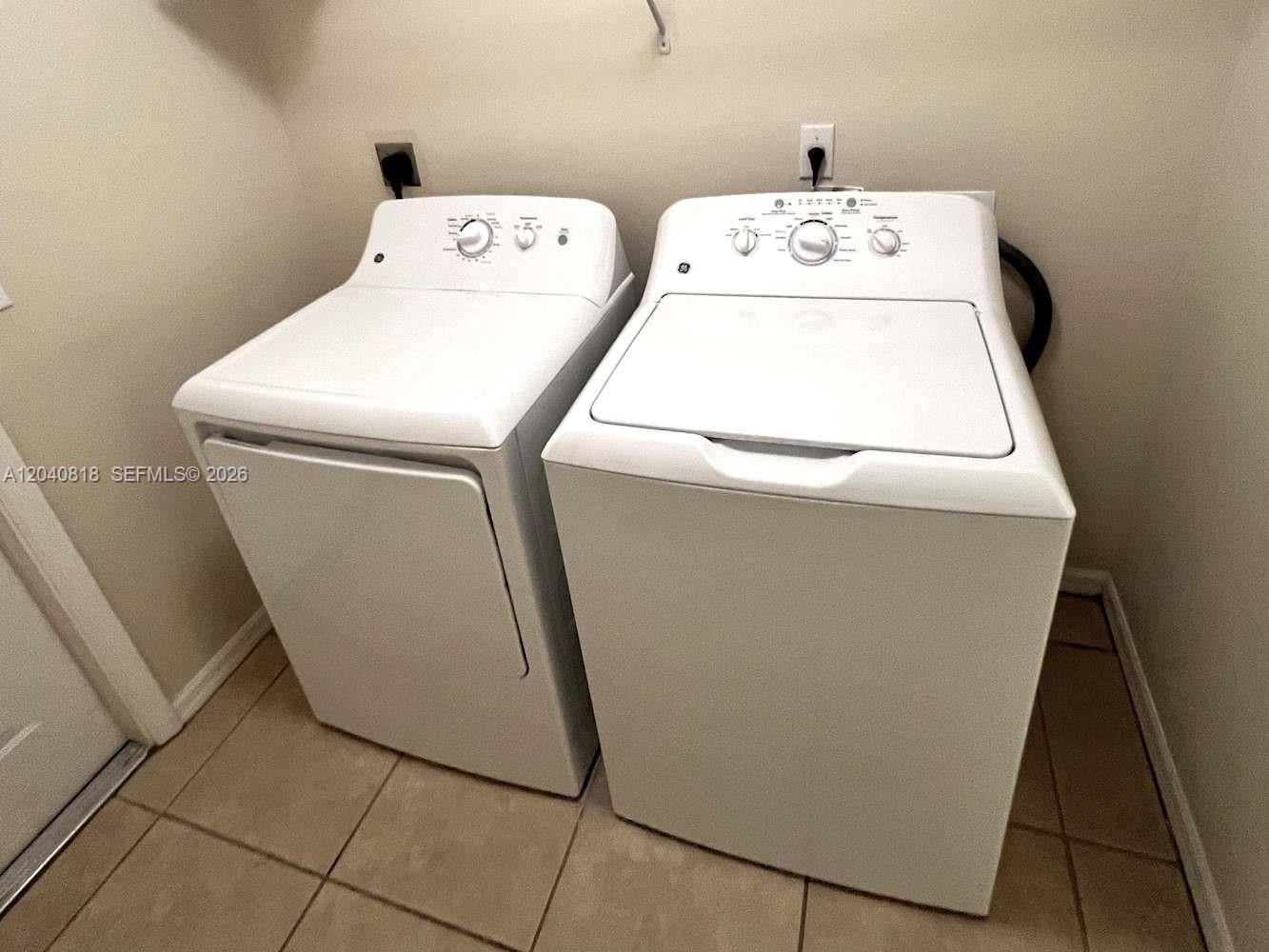 A laundry room features a white top-load washing machine and a matching dryer — PORT ST. LUCIE, FL