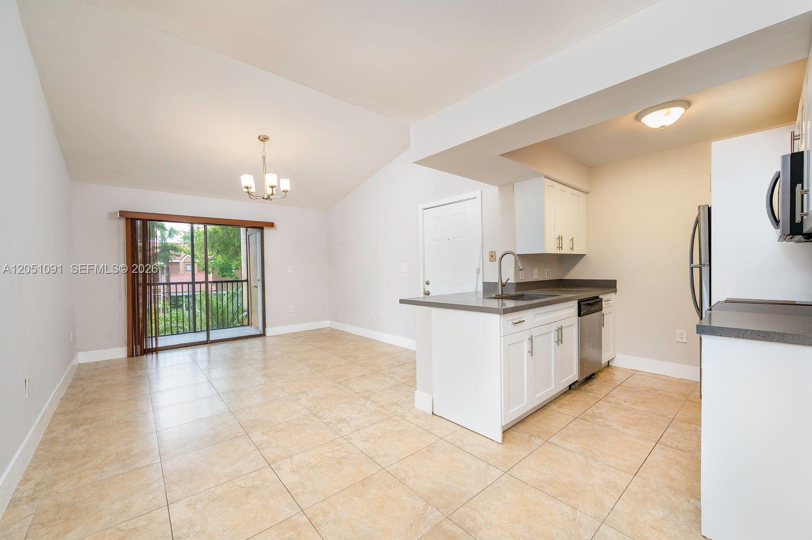 An open-concept kitchen and living area features tile flooring, white cabinetry, and a balcony — 15560 SW 104th Ter # 629, Miami FL 33196, MIAMI, FL